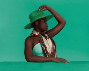 Portrait of a young woman in a green hat with a stylish scarf, exuding contemporary fashion and elegance.