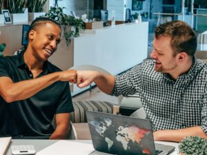 Two colleagues exchange a fist bump in a modern office. Collaborative and friendly work environment.